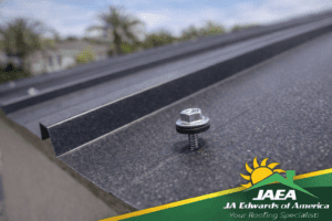 Close-up of correct screw and washer placement on an exposed-fastener steel roof panel.